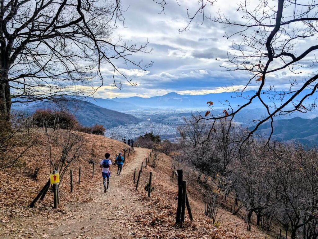 山頂付近の平坦なトレイルコースと、奥に見える街並みと空